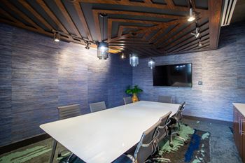 a conference room with a large white table and a tv